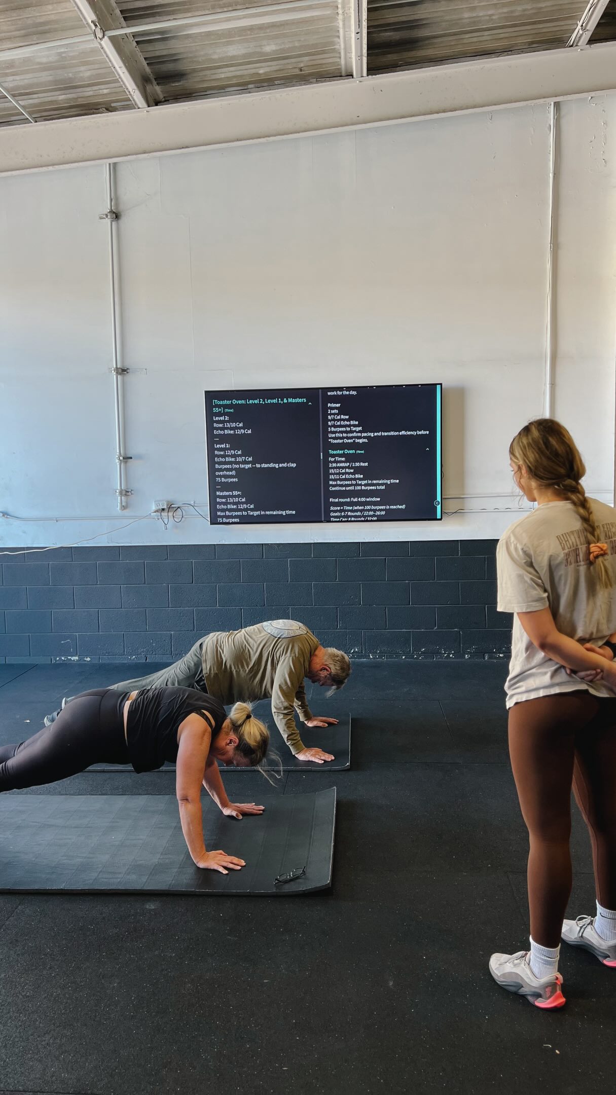 A coach scaling a workout for a beginner at O-SEA CrossFit