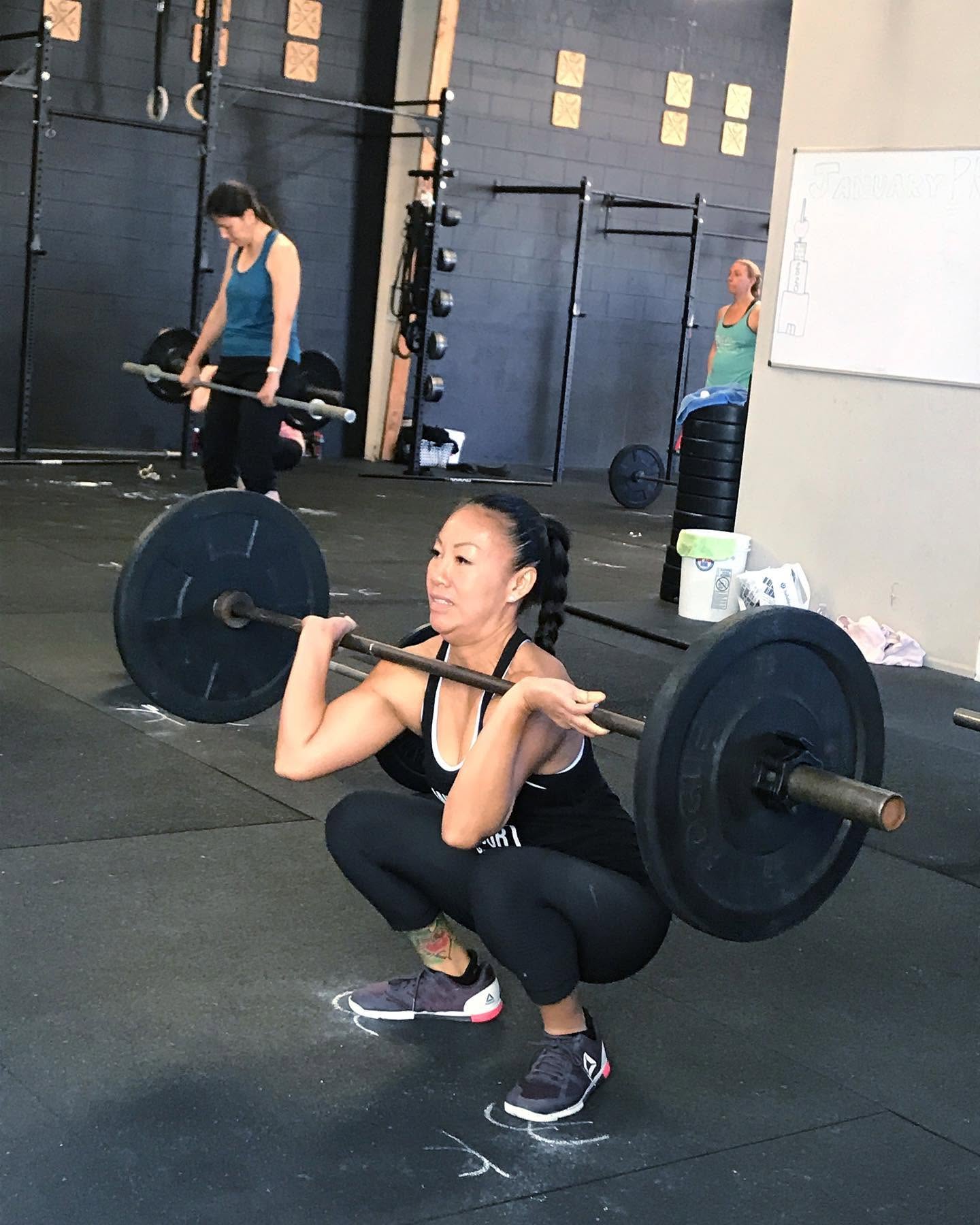 A member squatting with coaching at O-SEA CrossFit in San Clemente