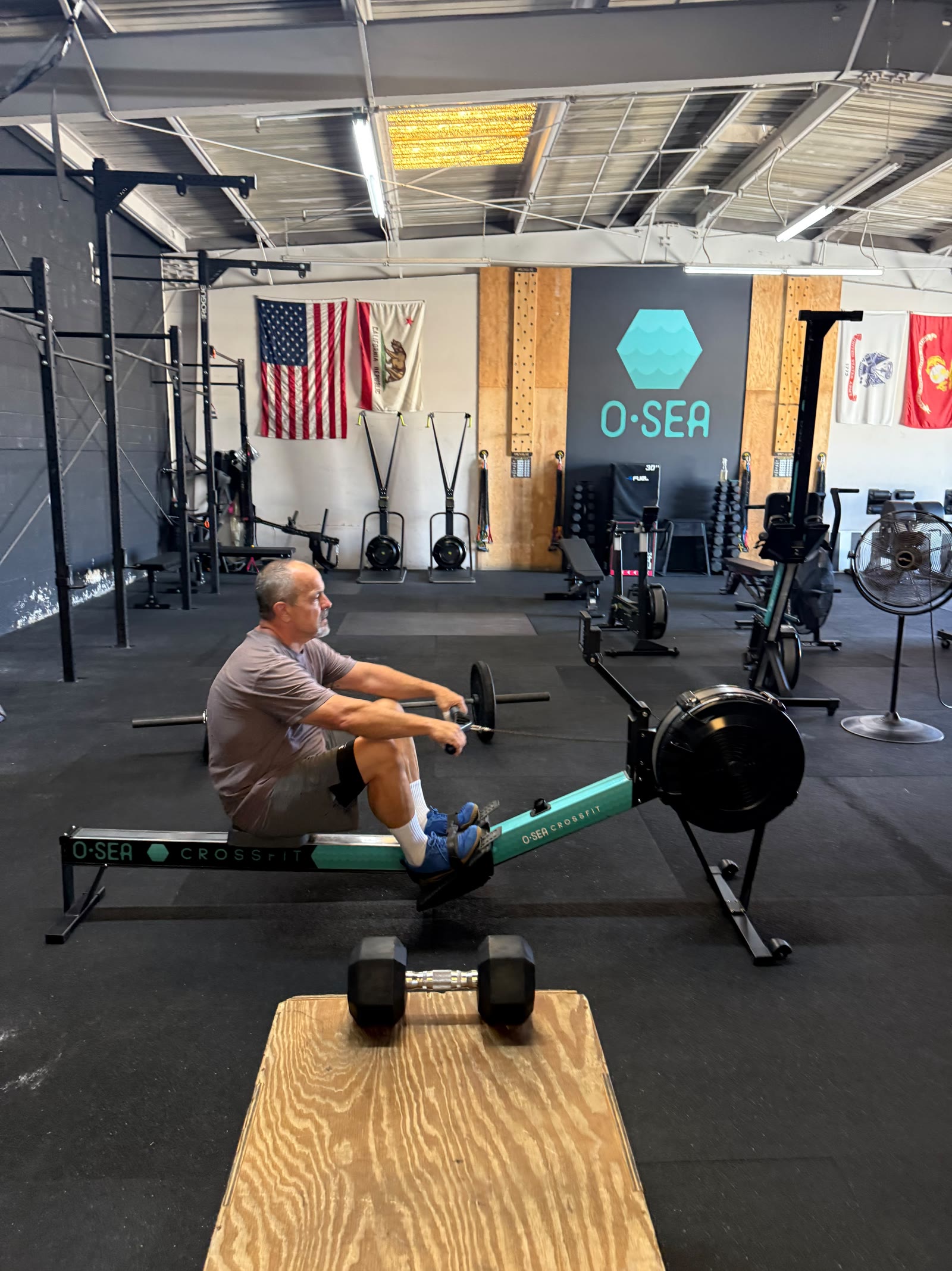 Man rowing with O-SEA logo wall and flags in background